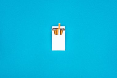 Top view of white cigarette pack isolated on blue  clipart