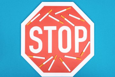Studio shot of stop sign and cigarettes isolated on blue, stop smoking concept clipart