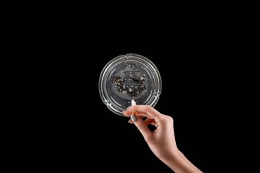 Cropped view of woman with manicure using glass ashtray isolated on black clipart