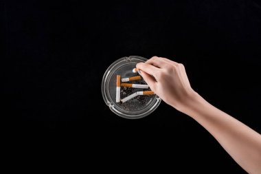 Cropped view of woman puts out cigarette in ashtray isolated on black clipart