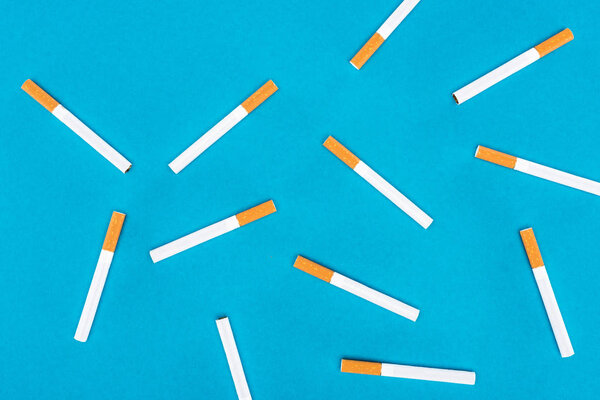 Flat lay of cigarettes isolated on blue 