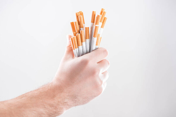 Cropped view of man holding cigarettes in hand isolated on grey