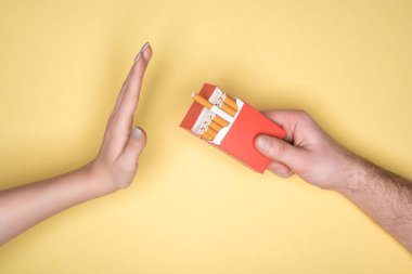 Cropped view of young woman refuses cigarettes isolated on yellow, stop smoking concept clipart