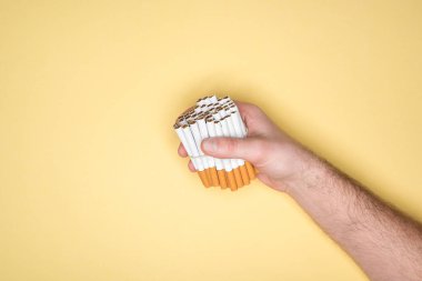 Sigara yumruk sarı izole içinde tutan adamın kısmi görünümü