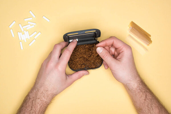 Обрезанный вид человека, держащего табачную коробку изолированной на желтый
