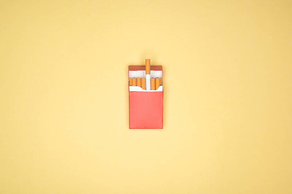 Студийный снимок красной пачки сигарет, изолированных на желтом
 