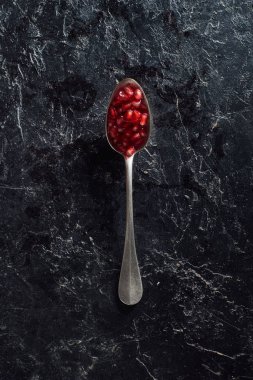 Top view of spoon with pomegranate seeds on dark surface clipart