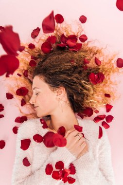 güzel kız ve düşen gül yaprakları üzerinde pembe izole üstten görünüm