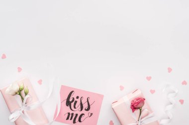 top view of gift boxes, paper hearts and card with 'kiss me' lettering isolated on white clipart