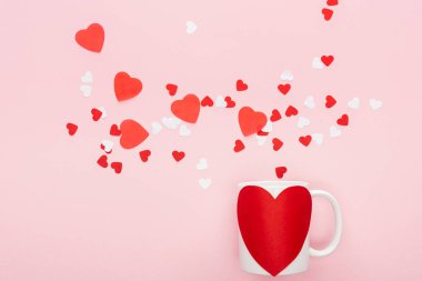 top view of paper hearts and cup with heart shaped sticker isolated on pink, st valentines day concept clipart