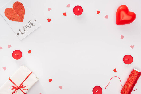 top view of gift box, paper hearts and greeting card with 'love' lettering isolated on white with copy space, st valentines day concept