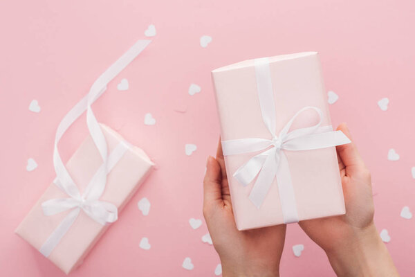 обрезанный вид женщины, держащей подарочную коробку изолированы на розовый
