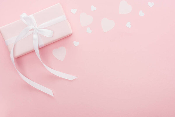 top view of gift box and paper hearts isolated on pink with copy space