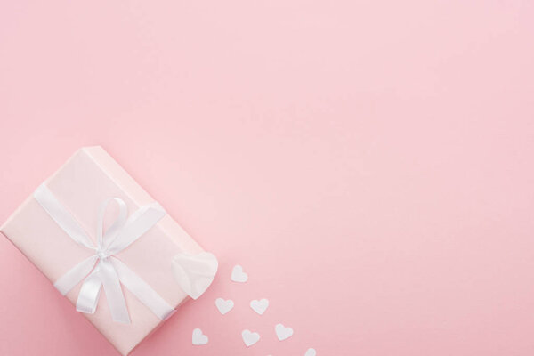 top view of gift box and paper hearts isolated on pink with copy space