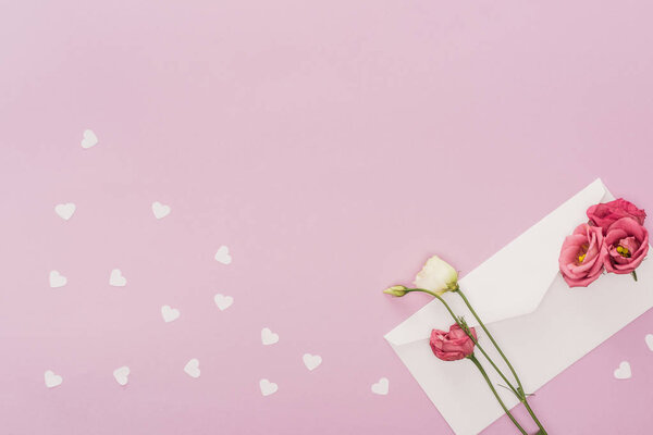 top view of envelope, flowers and paper hearts isolated on pink