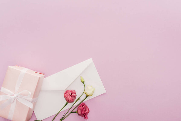 top view of gift box, envelope and flowers isolated on pink with copy space