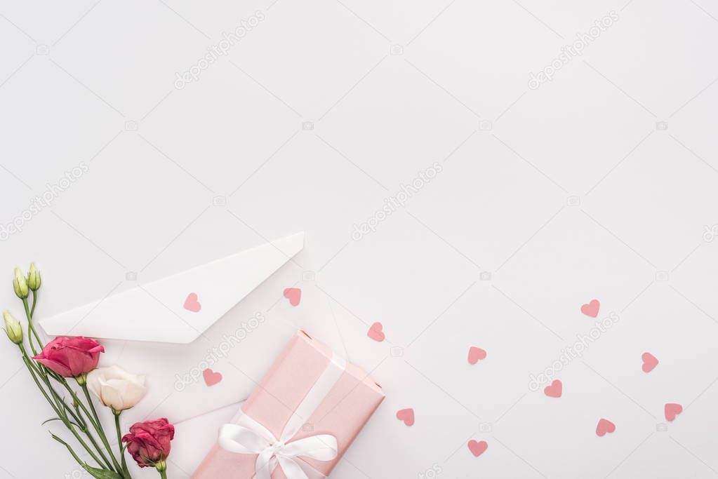 top view of gift box, flowers, envelope and paper hearts isolated on white