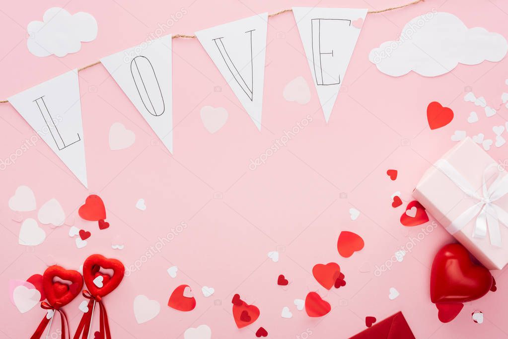 top view of valentines decorations and paper garland with 'love' lettering isolated on pink with copy space, st valentines day concept