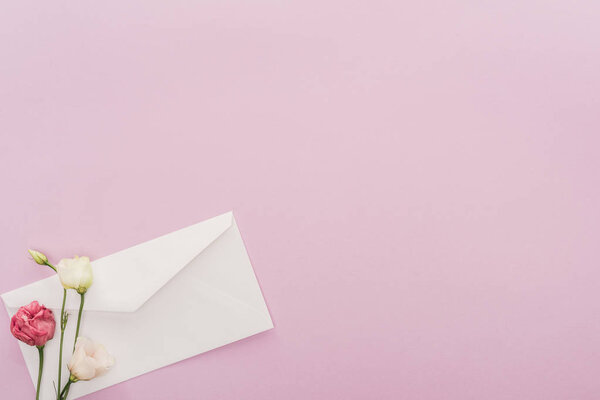 top view of flowers and envelope isolated on pink with copy space