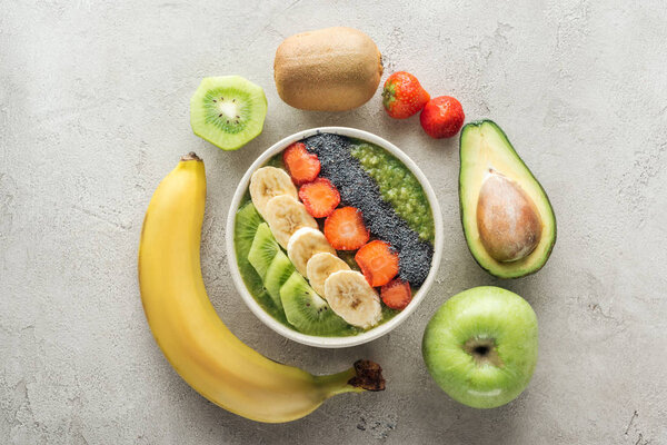 top view of smoothie bowl with fresh fruits and ingredients on grey background