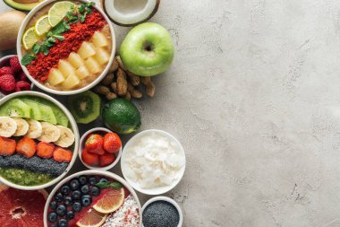 gri arka plan üzerinde malzemelerle sağlıklı güler yüzlü üstten görünüm kaseler