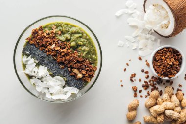 Beyaz arka plan üzerinde taze yeşil smoothie kase malzemelerle üstten görünüm