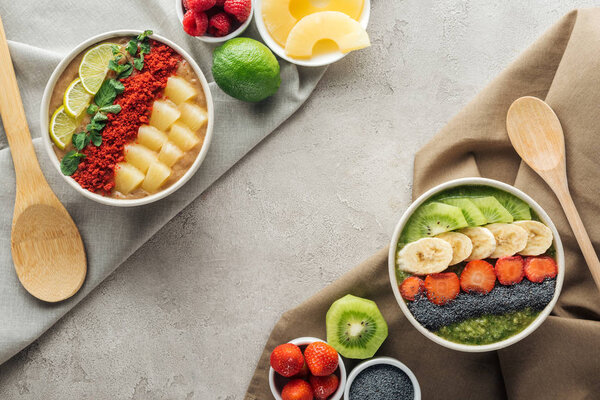 top view of delicious smoothie bowls with ingredients on tablecloths