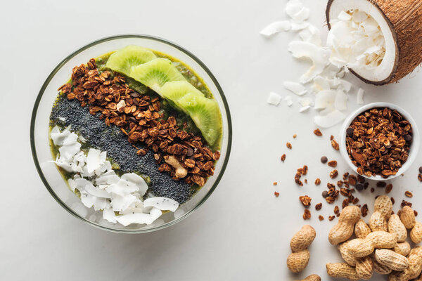 top view of healthy green smoothie bowl with ingredients on white background