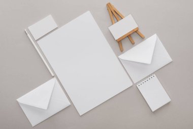 düz lay ile beyaz boş makaleler ve mektuplar ile oyuncak şövale gri arka plan üzerinde işyerinde