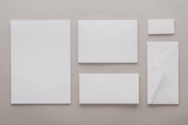 top view of empty papers and envelope with copy space on grey background