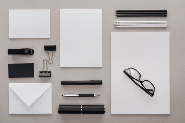 flat lay with black and white stationery and glasses at workplace on grey background