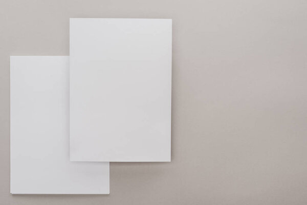 top view of white empty papers on grey background
