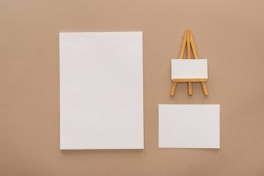 Boş yaprak kağıt ve oyuncak şövale bej renkli arka plan üzerinde