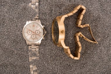 top view of wristwatches lying on golden sand  clipart