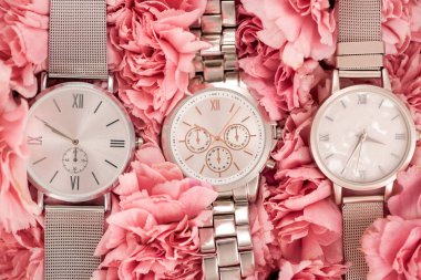 top view of wristwatches lying on blooming pink carnations  clipart