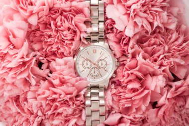 top view of elegant wristwatch lying on blooming flowers clipart