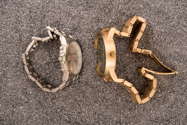 top view of wristwatches lying on sand 
