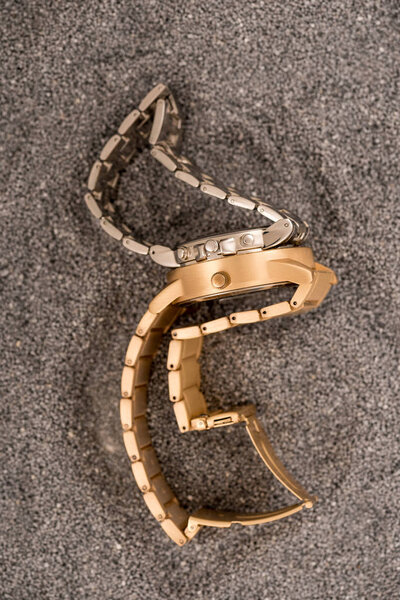 top view of luxury golden wristwatches lying on sand 
