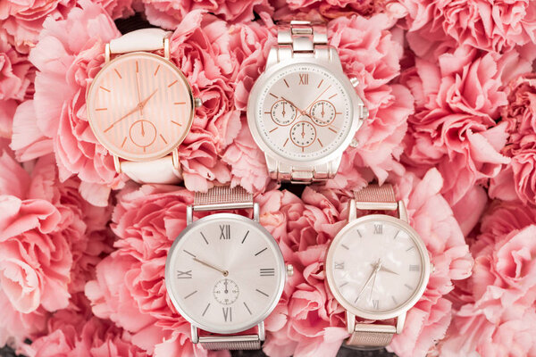 top view of wristwatches lying on blooming pink flowers 
