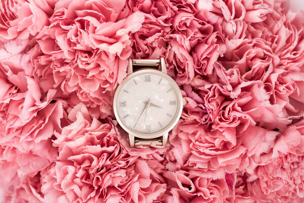 top view of luxury swiss wristwatch lying on blooming flowers