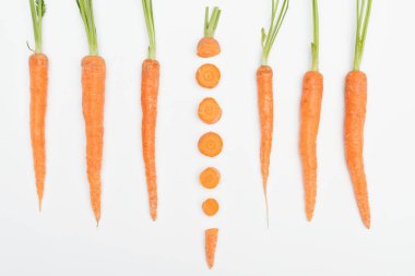 top view of composition with whole carrots with one sliced carrot in center isolated on white clipart