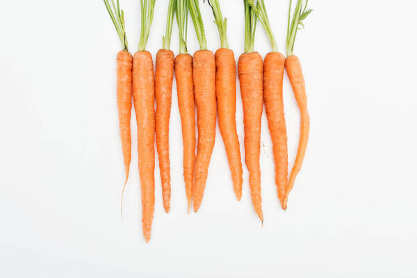 whole fresh ripe raw carrots arranged in tight row isolated on white