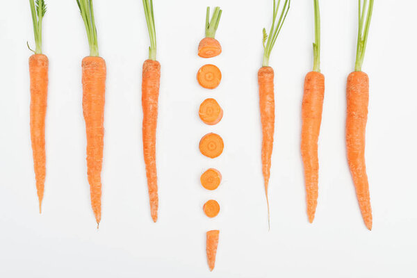 top view of composition with whole carrots with one sliced carrot in center isolated on white