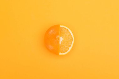 top view of fresh ripe partially cut orange on orange background clipart