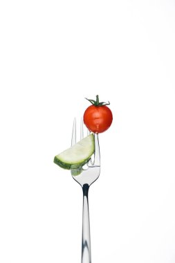 whole red cherry tomato and slice of cucumber on fork isolated on white