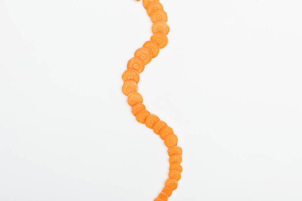 верхний вид спелых сырых ломтиков моркови, расположенных вертикально изогнутой линии, изолированных на белом
