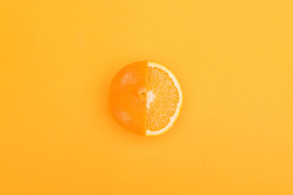 top view of fresh ripe partially cut orange on orange background