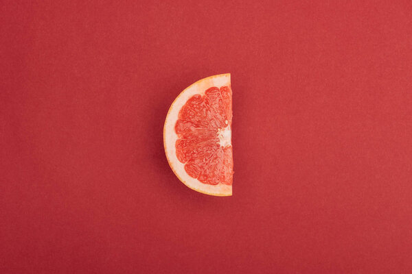 top view of half slice of fresh ripe juicy grapefruit red background