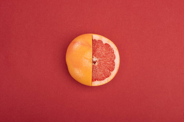 top view of fresh ripe partially cut grapefruit on red background