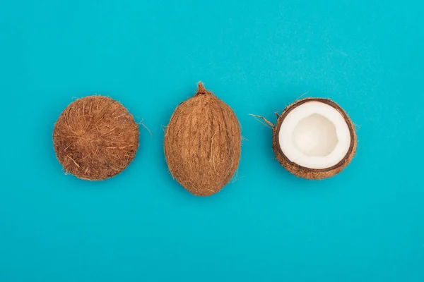 Draufsicht Auf Ganze Kokosnuss Und Kokosnusshälften Auf Blauem Hintergrund — Stockfoto